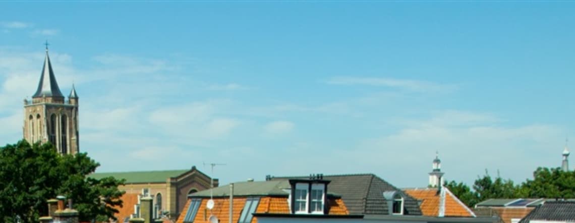 Daken en kerktoren van Gorinchem onder een blauwe lucht
