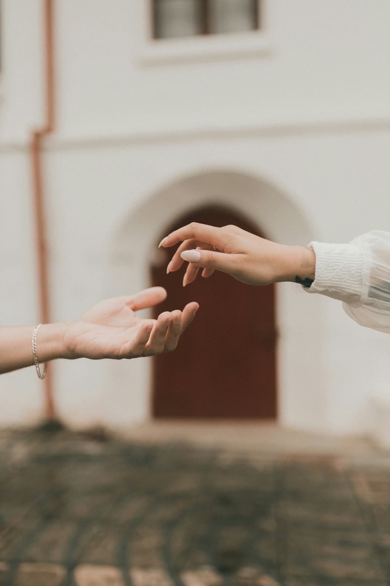 Twee handen die naar elkaar reiken voor een gebouw
